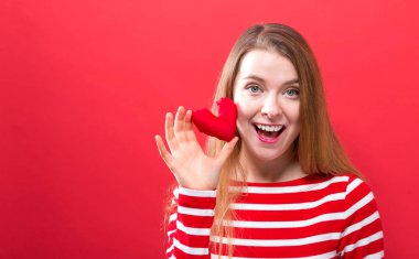 Bir kalp yastık tutan mutlu genç kadın