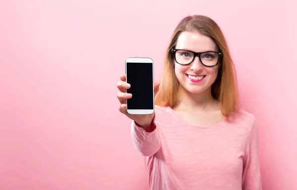 Ung kvinna håller ut en mobiltelefon — Stockfoto