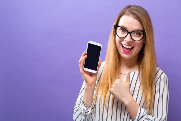 Ung kvinna håller ut en mobiltelefon — Stockfoto