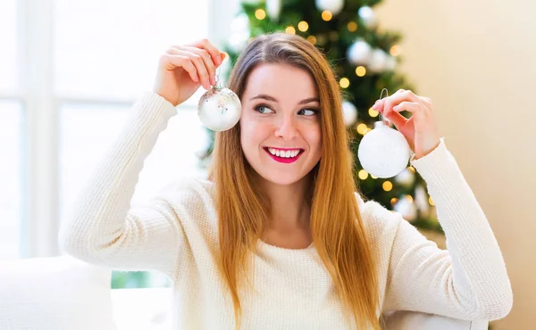 Mujer feliz sosteniendo adornos de Navidad en su casa — Foto de Stock