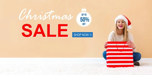 Försäljning julhälsning med kvinna med Santa hatt hålla en shopping väska — Stockfoto