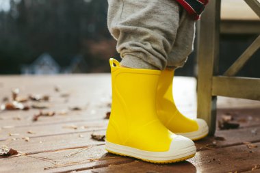 Yürümeye başlayan çocuk onun yelllow yağmur botlar ile oynamak