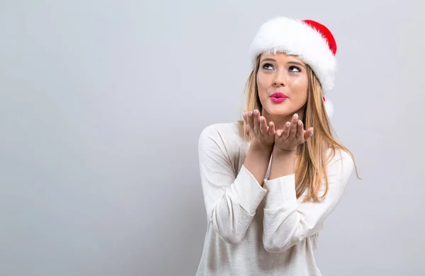 Gelukkig jonge vrouw met KERSTMUTS blaast een kus — Stockfoto