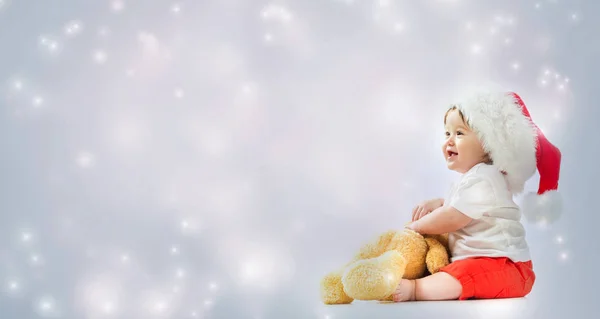 Kleinkind mit Weihnachtsmann spielt mit seinem Teddybär — Stockfoto