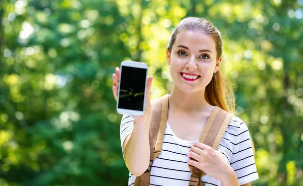 Ung kvinna håller ut en smartphone — Stockfoto