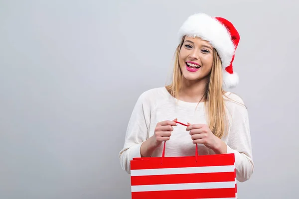 Jeune femme avec santa chapeau tenant un sac à provisions — Photo