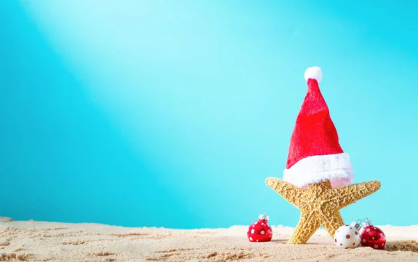 Étoile de mer avec chapeau de Père Noël sur la plage avec des ornements de Noël — Photo