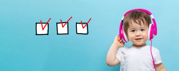 Lista kontrolna z toddler chłopiec ze słuchawkami — Zdjęcie stockowe