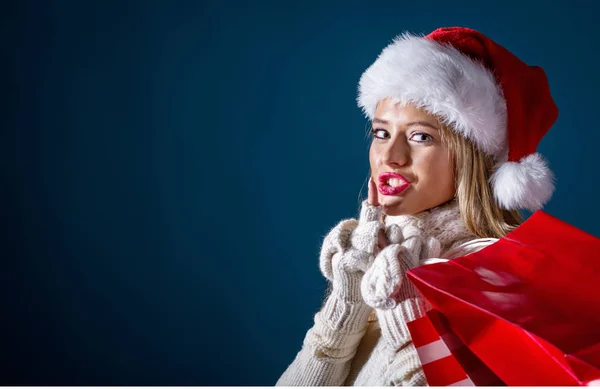 Mujer joven con sombrero de Santa sosteniendo bolsas de compras — Foto de Stock