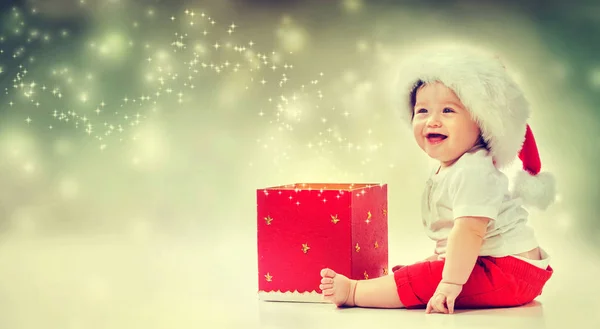 Bambino con cappello da Babbo Natale che apre una confezione regalo — Foto Stock