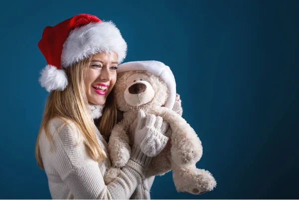 Jeune femme avec un chapeau de Père Noël tenant un ours en peluche — Photo