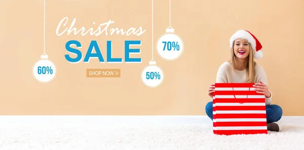 Försäljning julhälsning med kvinna med Santa hatt hålla en shopping väska — Stockfoto