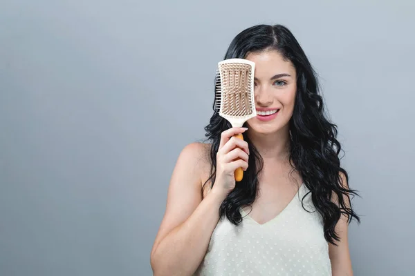 Belle jeune femme tenant une brosse à cheveux — Photo