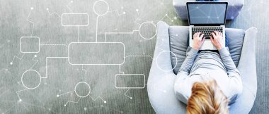 Akış çizelgesi ile bir dizüstü bilgisayar kullanan adam