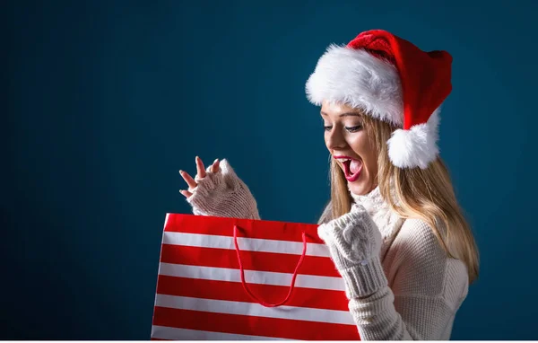 Jovem com chapéu de santa segurando um saco de compras — Fotografia de Stock