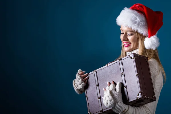 Mladá žena s kloboukem santa držící kufr — Stock fotografie