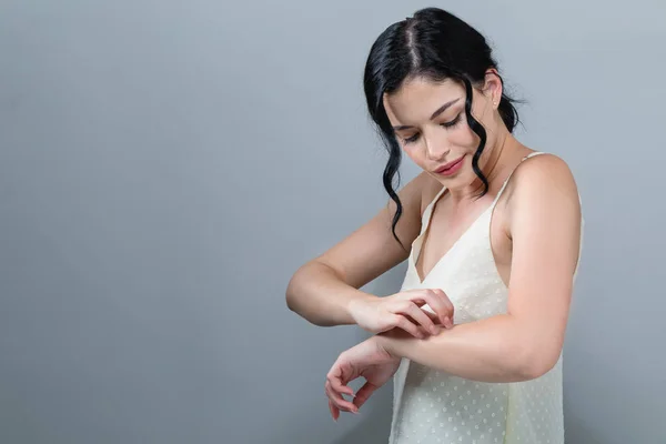 Jovem mulher coçando seu braço coceira . — Fotografia de Stock