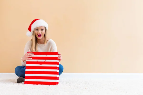 Jovem com chapéu de santa segurando um saco de compras — Fotografia de Stock