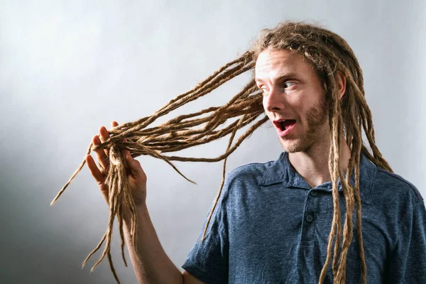 Mand med dreadlocks kigger på hans hår - Stock-foto