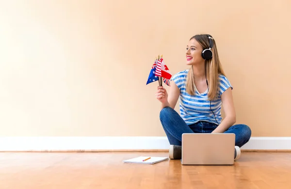 Giovane donna con bandiere di paese di lingua inglese con computer portatile — Foto Stock