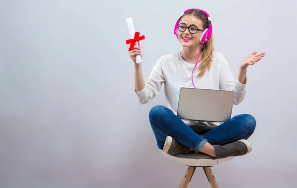 Mladá žena držící diplom a její laptop — Stock fotografie