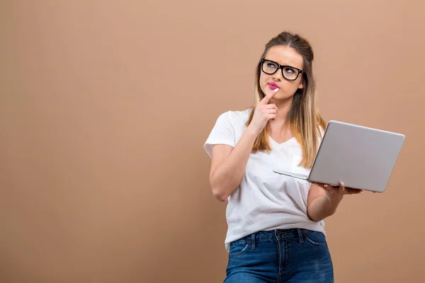 Mulher nova com um computador portátil em uma pose pensativa — Fotografia de Stock