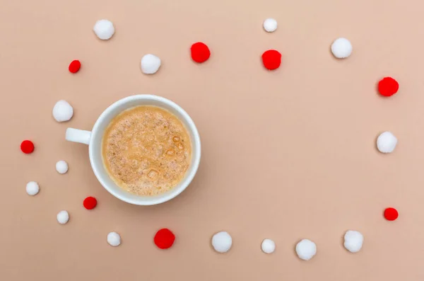 Cup of coffee with Christmas pompoms on brown paper — Stock Photo, Image