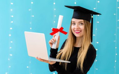 Genç kadın bir mezuniyet diploması ve dizüstü bilgisayar ile
