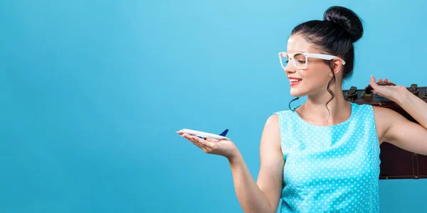 Giovane donna con una valigia e giocattolo aereo tema di viaggio — Foto Stock