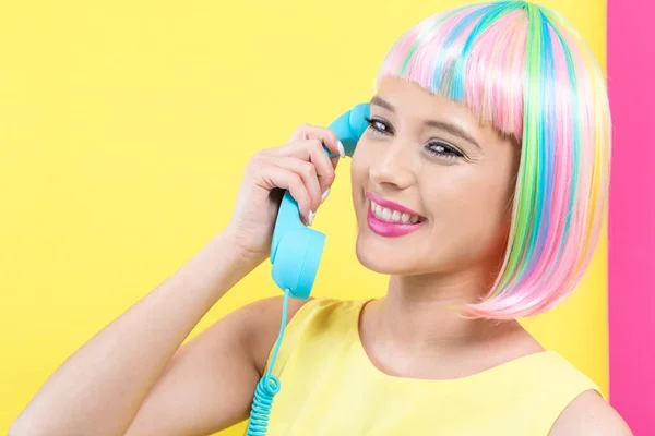 Jovem mulher em uma peruca colorida falando em um telefone retro — Fotografia de Stock