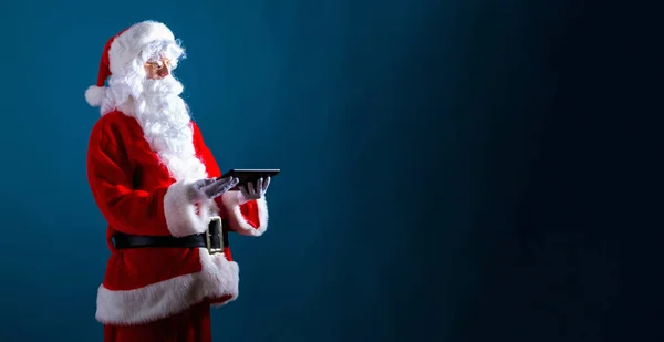 Santa segurando um computador tablet — Fotografia de Stock