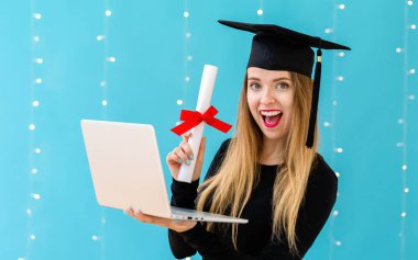Genç kadın bir mezuniyet diploması ve dizüstü bilgisayar ile