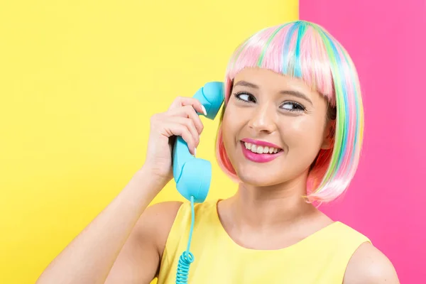 Молода жінка в барвистій перуці говорить на ретро телефоні — стокове фото