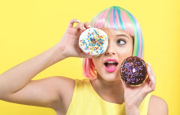 Mulher bonita em uma peruca colorida com donuts — Fotografia de Stock