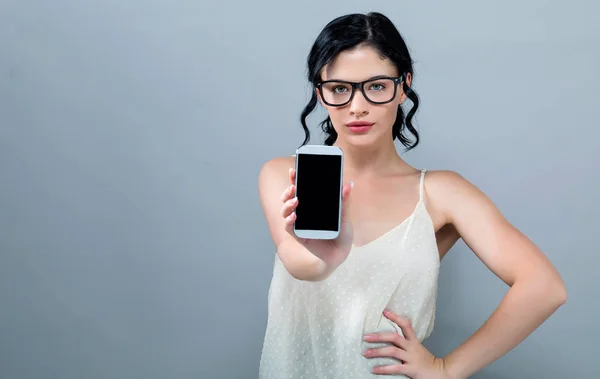 Ung kvinna håller ut en telefon i handen — Stockfoto