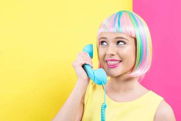 Jovem mulher em uma peruca colorida falando em um telefone retro — Fotografia de Stock