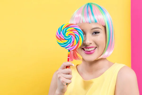 Mulher em uma peruca colorida com um pirulito — Fotografia de Stock