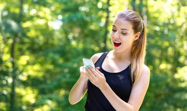 Ung kvinna som använder sin telefon — Stockfoto