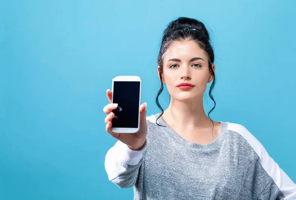 Giovane donna che tiene un telefono in mano — Foto Stock