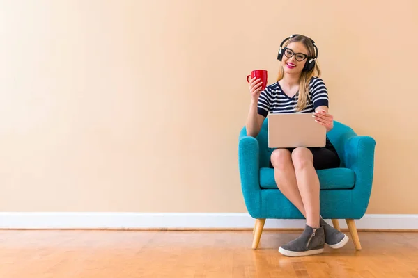 Jeune femme avec écouteurs et son ordinateur portable — Photo