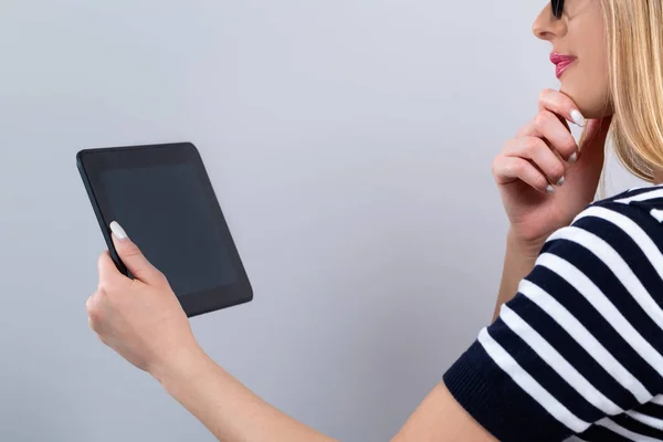 Jonge Vrouw Met Een Tabletcomputer Een Grijze Achtergrond — Stockfoto