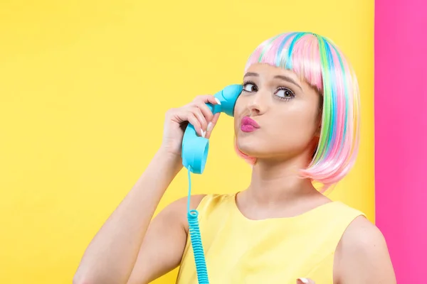 Giovane donna con una parrucca colorata che parla su un telefono retrò — Foto Stock