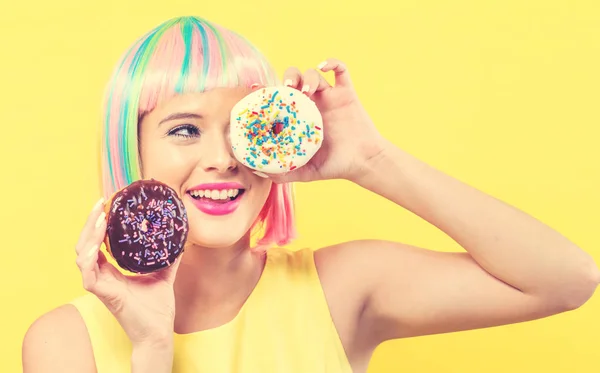 Mulher bonita em uma peruca colorida com donuts — Fotografia de Stock