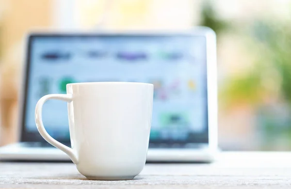 Koffiemok met laptop op een lichte achtergrond — Stockfoto