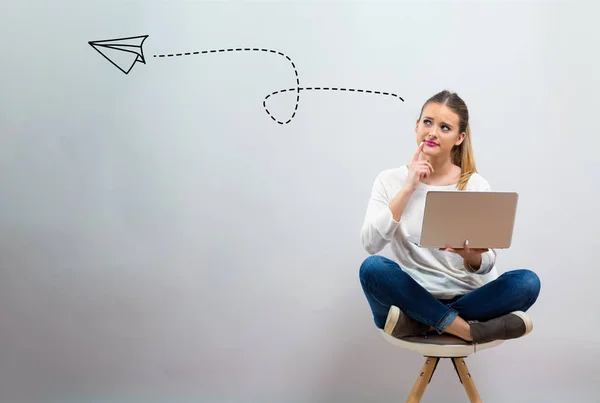 Papieren vliegtuigje tekenen met jonge vrouw haar laptop gebruikt — Stockfoto