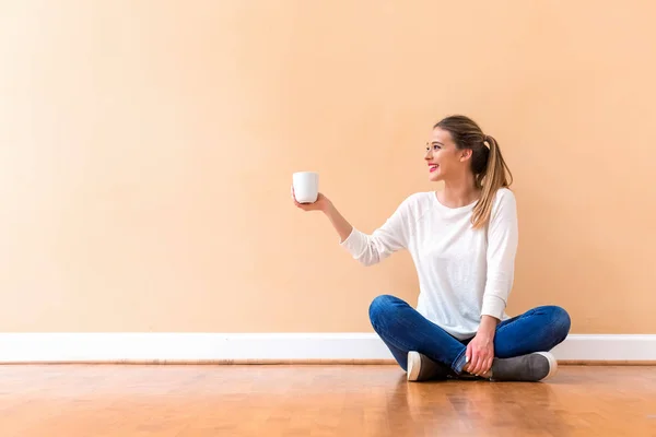 Mladá žena pije šálek kávy — Stock fotografie