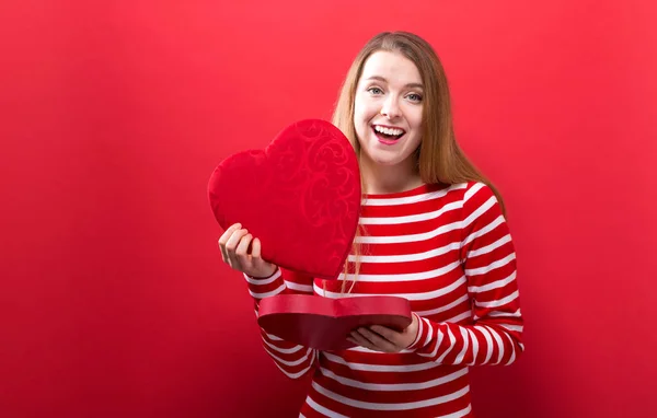 Glad ung kvinna håller en stort hjärta presentförpackning — Stockfoto