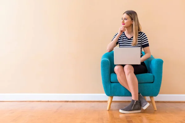 Mulher nova com um computador portátil em uma pose pensativa — Fotografia de Stock