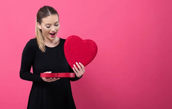 Mujer joven sosteniendo una gran caja de regalo de corazón — Foto de Stock