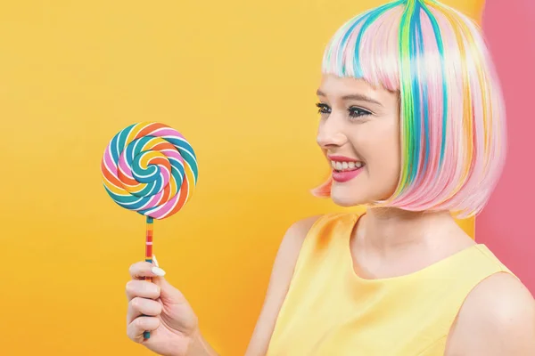 Mulher em uma peruca colorida com um pirulito — Fotografia de Stock